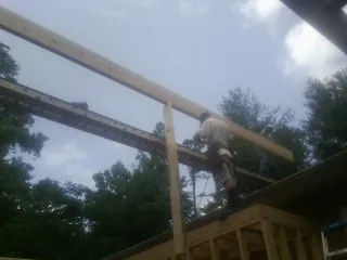 Carpenter setting a ridge beam over a new addition frame — Ice Dam Removal by Roofing Brothers in Melissa