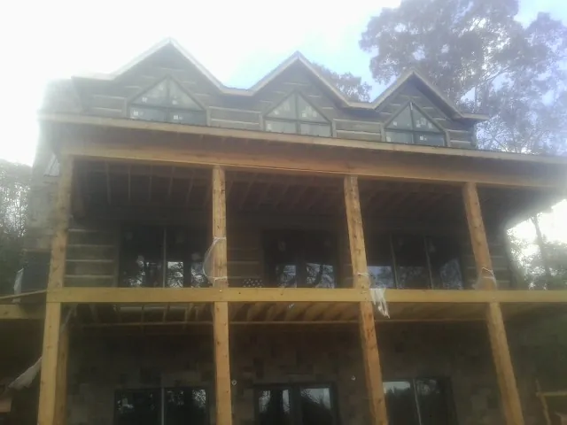 Dormers and porch framing on a large log home under construction — Roof Coating work by our crew in Melissa