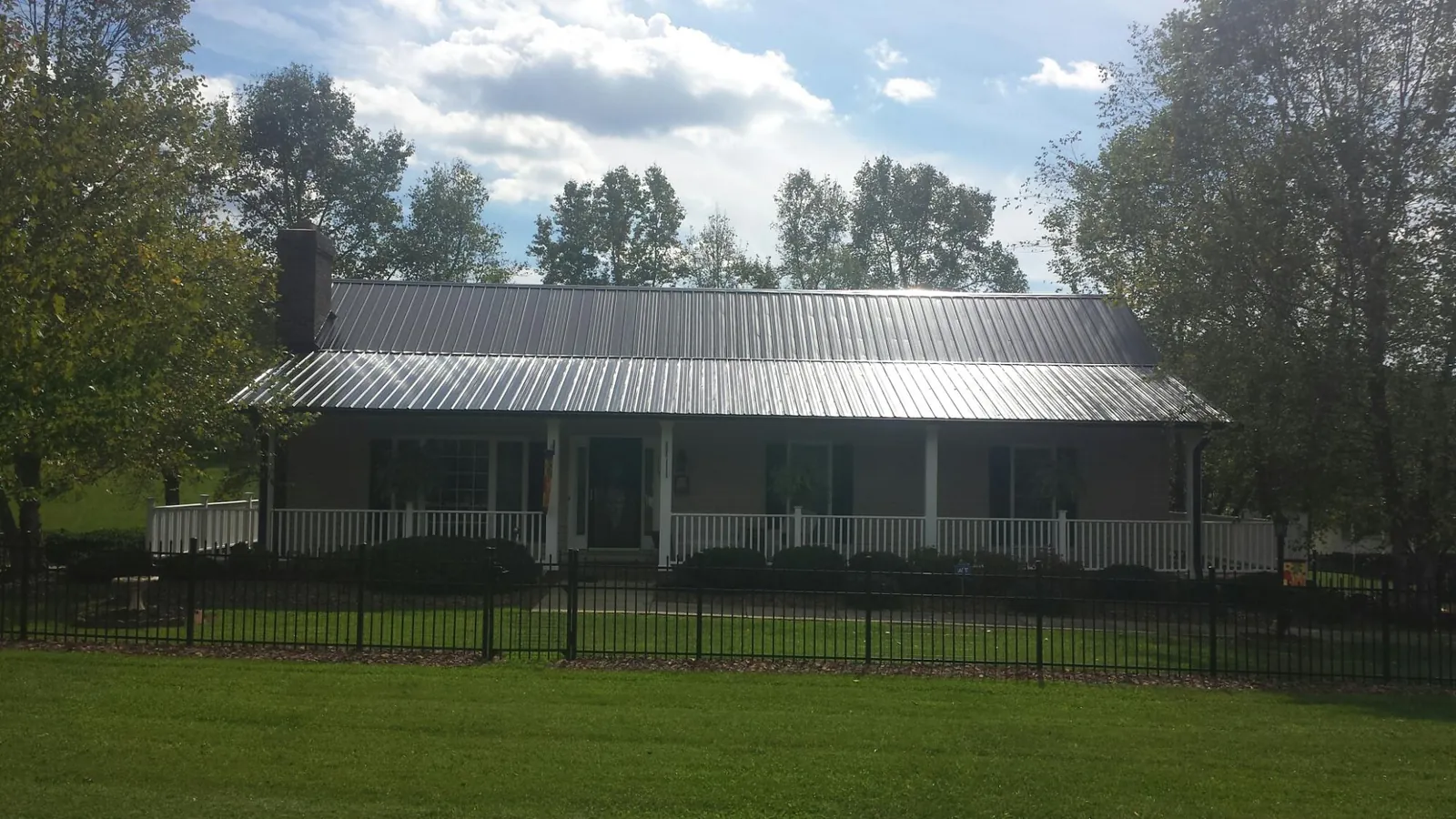 Gray metal roof on a brick ranch with a full width front porch — Gutter Guard Installation work by our crew in Melissa