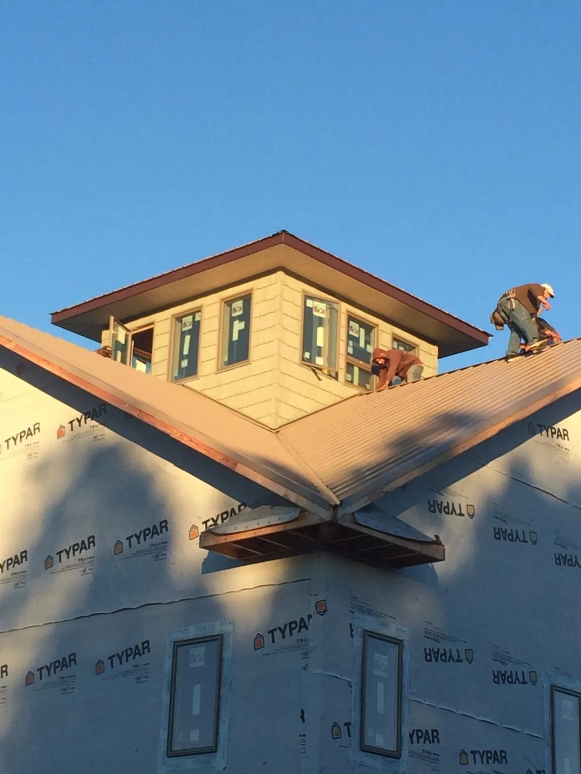Roofers working around a rooftop cupola on a new metal roof at sunset — Roof Waterproofing in Melissa by Roofing Brothers
